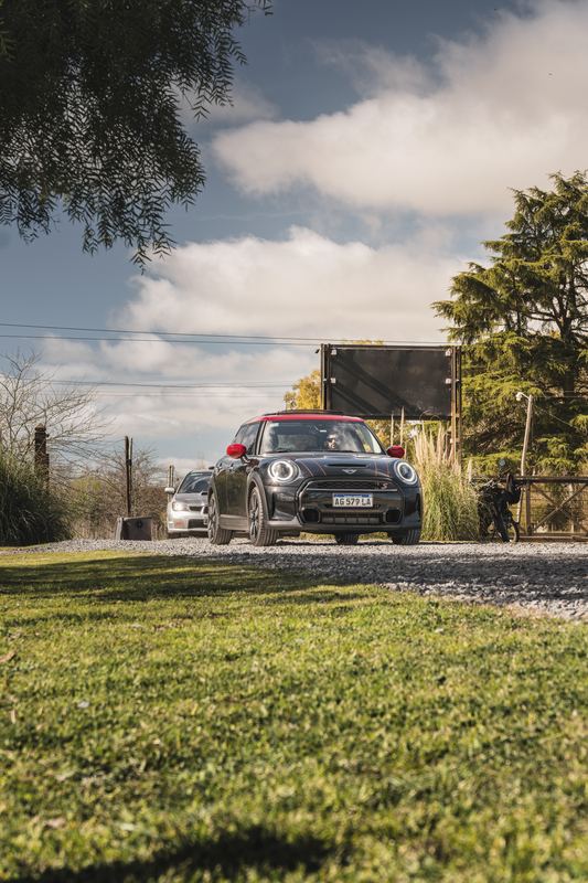 Mini JCW negro entrando por el portón, WRX detrás